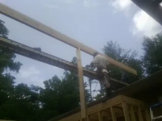 Carpenter setting a ridge beam over a new addition frame — Ice Dam Removal by Roofing Brothers in Tunnelton