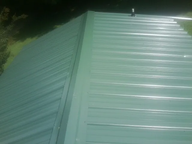 New green metal panels meeting at the ridge of a roof — Flat Roof Repair work by our crew in Tunnelton
