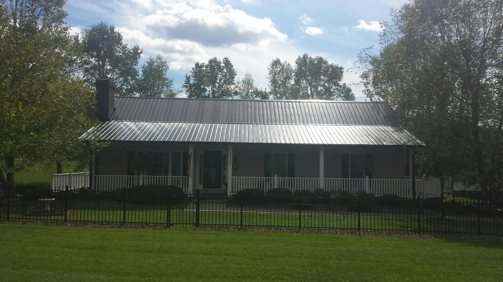 Gray metal roof on a brick ranch with a full width front porch — Gutter Guard Installation work by our crew in Tunnelton