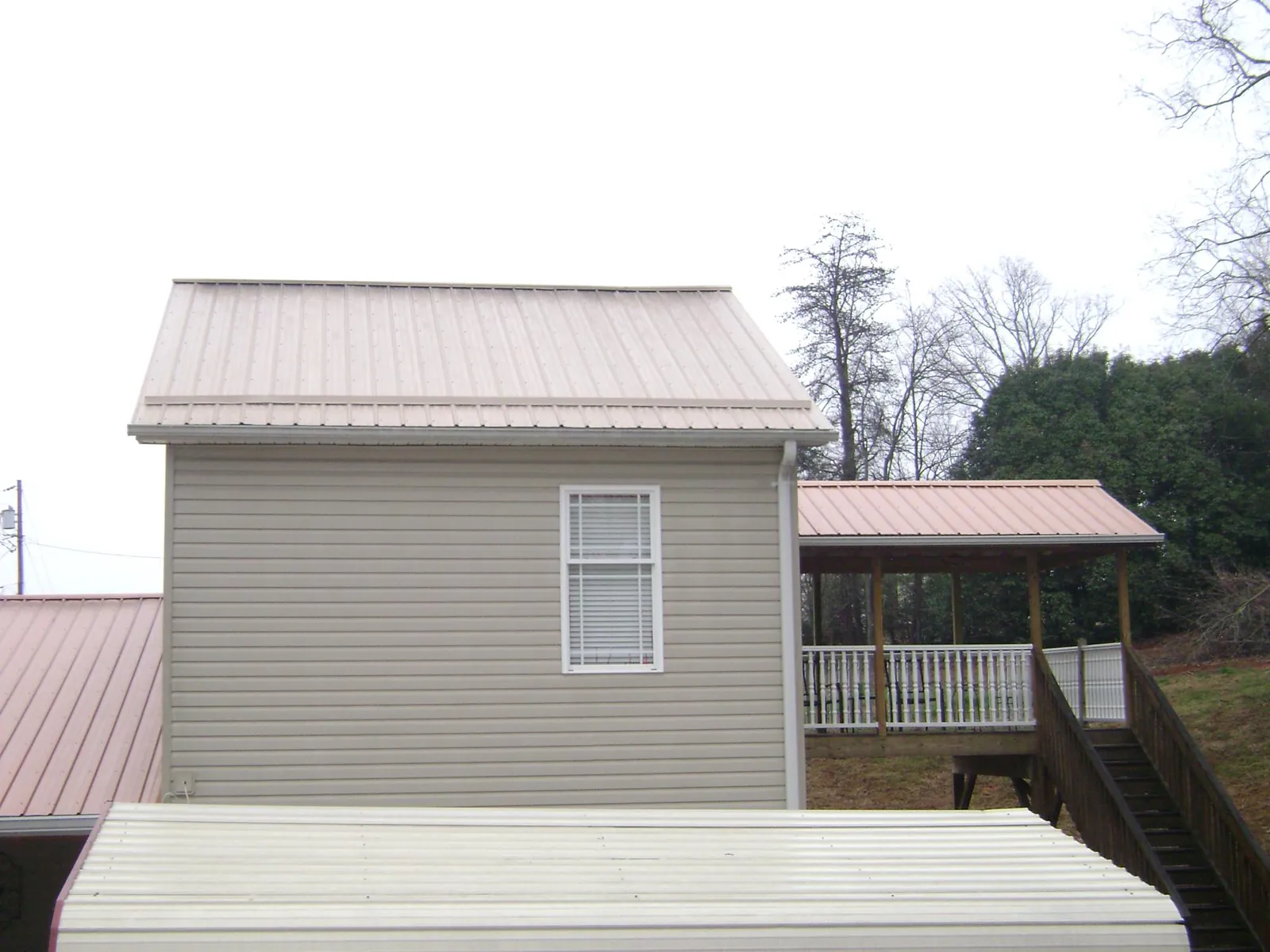 Tan metal roofs on a two story addition and attached porch, from a Roof Replacement job in Tunnelton