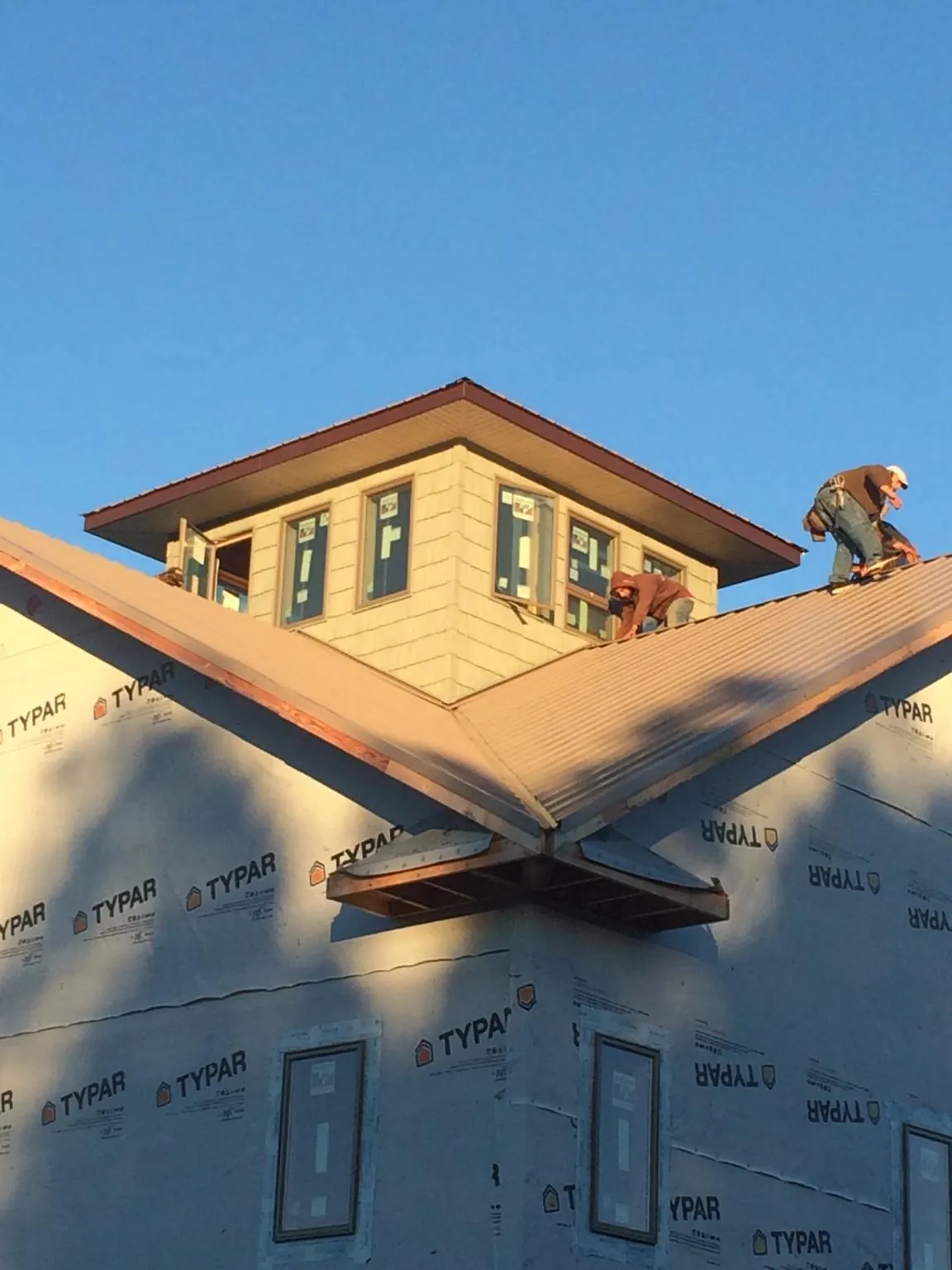 Roofers working around a rooftop cupola on a new metal roof at sunset — Roof Waterproofing in Tunnelton by Roofing Brothers